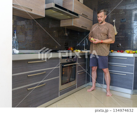 Man preparing a healthy apple snack. Domestic lifestyle in a modern kitchen 134974632