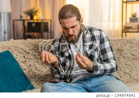 Young man anxious at home, urgent phone call on knee, frustration, loud speaker, intense quarrel 134974841