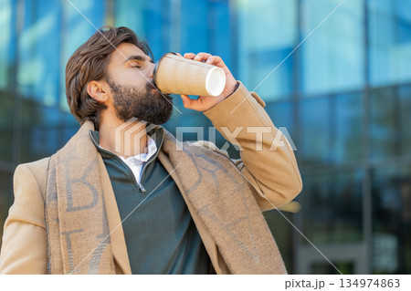 Happy Indian business man tourist enjoying morning coffee hot drink walking on city downtown street 134974863