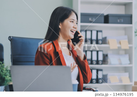 Serious charming woman using smartphone while working with laptop 134976195