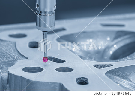 The multi-axis CMM machine measuring the aluminum cylinder head parts in the light blue scene. 134976646