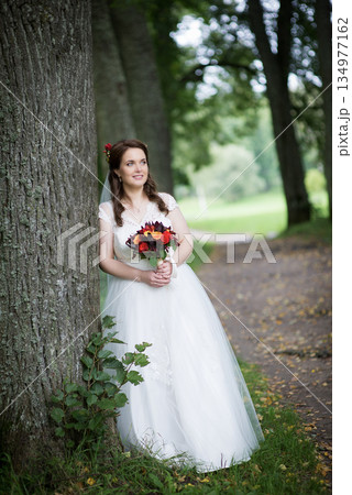 Young Bride Smiling Gently With Bouquet Young Bride Smiling Gently With Bouquet 134977162