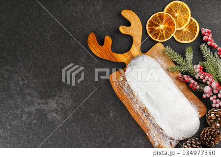 Traditional Christmas Stollen, sweet fruit loaf with sugar icing on wooden board and festive decor 134977350