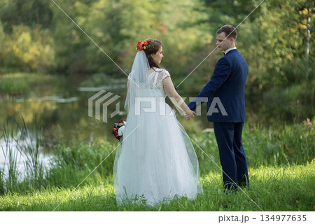 Young Wedding Couple Holding Hands By Water Young Wedding Couple Holding Hands By Water 134977635