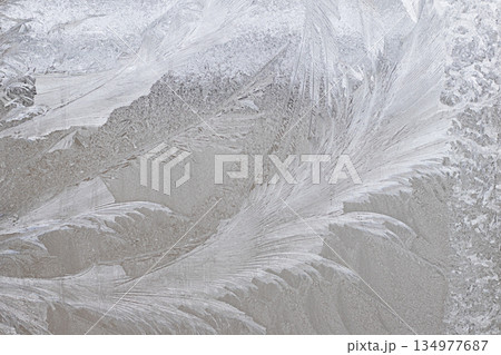 Frosted glass texture with intricate ice patterns and delicate winter glow Frosted glass texture with intricate ice patterns and delicate winter glow 134977687