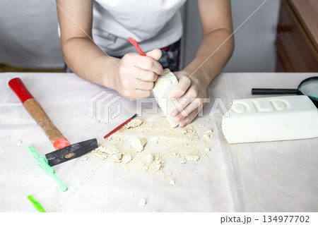 Child at craft table carving soap block with tools and shavings for a creative project 134977702