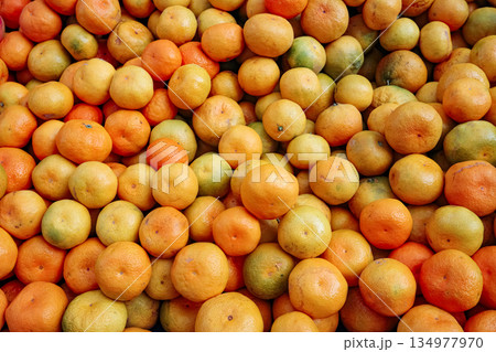 Closeup of many fresh ripe tangerines with natural imperfect skin texture, full frame citrus background for food market or healthy lifestyle concepts 134977970