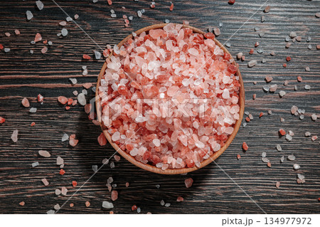 Wooden bowl filled with pink Himalayan salt crystals on dark wooden table, natural mineral seasoning for healthy cooking and spa concepts. Wooden bowl filled with pink Himalayan salt crystals on dark wooden table, natural mineral seasoning for healthy cooking and spa concepts. 134977972