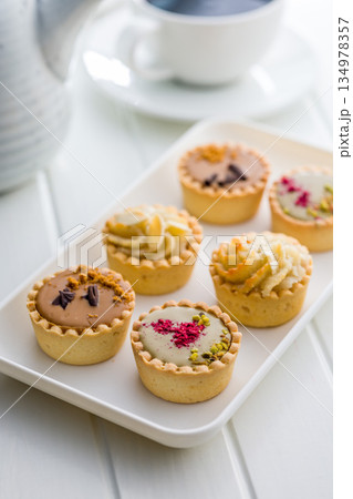 Sweet mini tartlets on plate on white table. 134978357