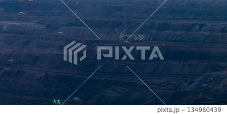 Ultra high resolution panoramic view of massive mining machines operating in an open pit coal mine, surrounded by dust and dramatic light. Powerful industrial scene showing large scale extraction, 134980439