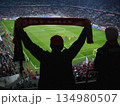 Man is holding a red scarf and is watching a soccer game 134980507