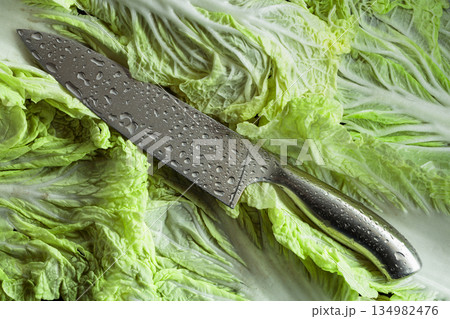 Kitchen knife with water drops on a fresh Chinese cabbage leaves. Kitchen knife with water drops on a fresh Chinese cabbage leaves. 134982476
