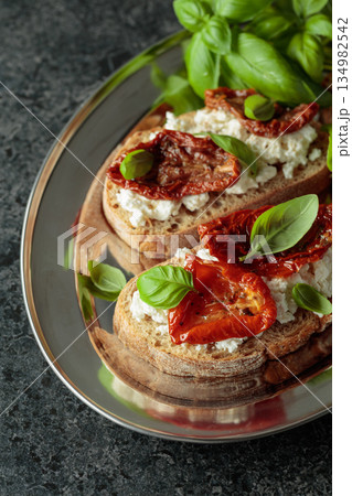 Ciabatta with sun dried tomatoes in olive oil, ricotta and basil. 134982542