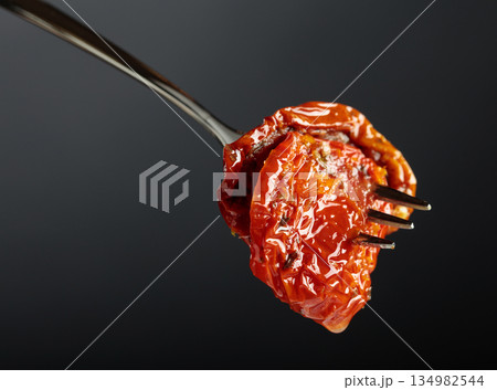 Sun dried tomatoes in olive oil on a fork. Sun dried tomatoes in olive oil on a fork. 134982544