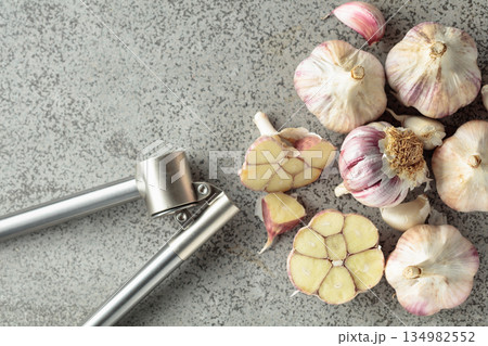 Garlic and garlic press on a kitchen table. 134982552