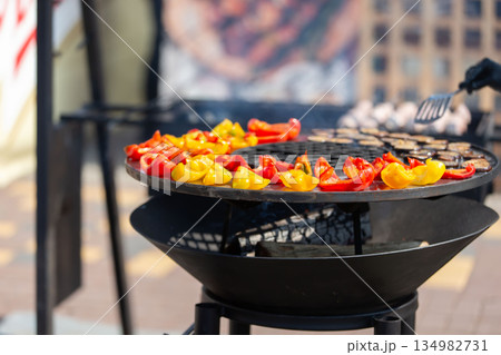 Colorful peppers grilling at an outdoor culinary event in a city Colorful peppers grilling at an outdoor culinary event in a city 134982731
