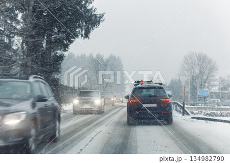 Scenic view snow covered city highway slippery mountain alpine road drive cars moving fast speed motion. Snowfall danger blizzard bad winter weather conditions. Cold snowy day snowstorm background Scenic view snow covered city highway slippery mountain alpine road drive cars moving fast speed motion. Snowfall danger blizzard bad winter weather conditions. Cold snowy day snowstorm background 134982790