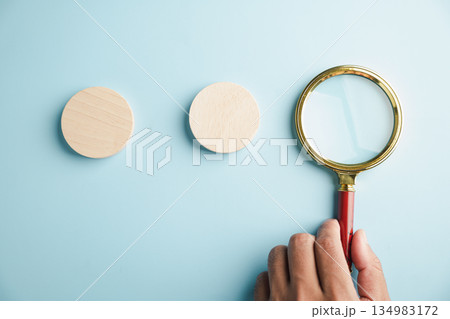 Sign of searching in this man hand pose and gesture closeup, he holds a magnifying glass over a blank wooden sign which is a symbol for finding the right business solution. 134983172