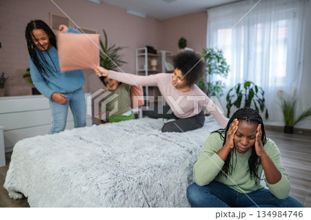 Stressed mother experiencing headache as children play in background Stressed mother experiencing headache as children play in background 134984746
