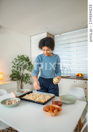 Woman preparing homemade pizza topping with fresh ingredients Woman preparing homemade pizza topping with fresh ingredients 134984838