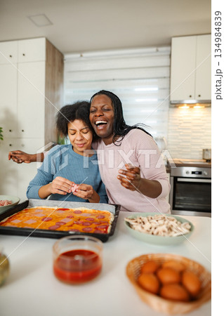 Mother and daughter bonding making pizza together 134984839