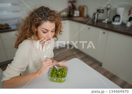 Woman eating fresh kiwi fruit for healthy diet breakfast 134984970