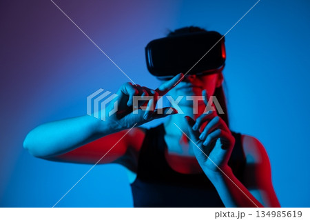 Young woman wearing VR headset performing hold gesture for virtual action confirmation Young woman wearing VR headset performing hold gesture for virtual action confirmation 134985619