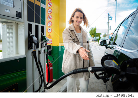 Woman smiling while refueling car at a gas station 134985643