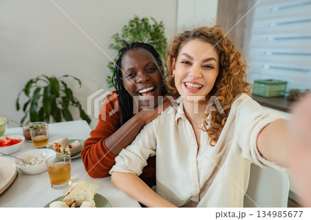Diverse friends taking selfie enjoying lunch at home Diverse friends taking selfie enjoying lunch at home 134985677
