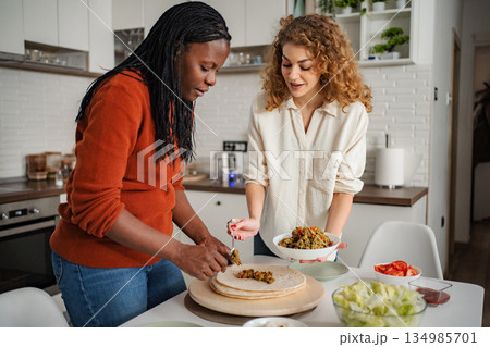 Friends preparing healthy tacos in domestic kitchen 134985701