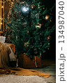 Decorated Christmas tree and cozy pallet sofa with a warm blanket, evoking a feeling of festive comfort. Holiday season interior decor for winter celebration. 134987040