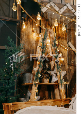 Decorated Christmas interior with glowing light bulbs and garland with evergreen pine branches and cones. Holiday decoration and festive mood. 134987041