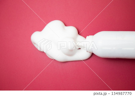 Close-up view from above in the center of the bottle of foam for long-lasting hair styling lies on a pink background, white foam has poured out of it. The concept of styling, fixing hair, hair care Close-up view from above in the center of the bottle of foam for long-lasting hair styling lies on a pink background, white foam has poured out of it. The concept of styling, fixing hair, hair care 134987770