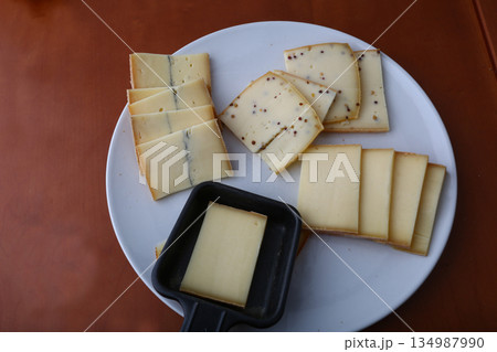 sliced cheese pieces for a traditional raclette lunch 134987990