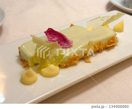 Elegant plated dessert with creamy glaze and decorative garnish on white plate. Fine dining aesthetics, culinary artistry, refined sweetness, and modern restaurant dessert presentation. 134988060