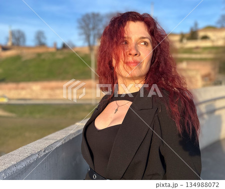 Woman portrait in warm evening light near city bridge. Femininity, confidence, emotional depth, and quiet strength in urban surroundings 134988072