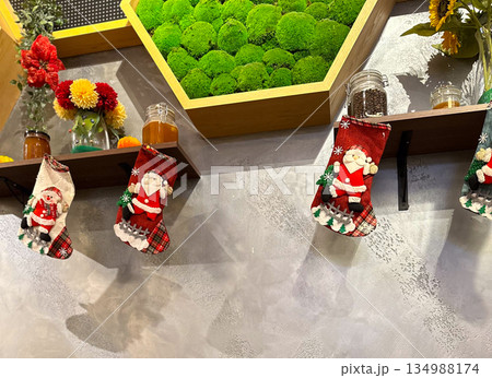 Christmas stockings hanging on wall shelf with festive decor. Seasonal styling, holiday atmosphere, interior design detail, winter tradition, and cozy decorative accents in public space. Christmas stockings hanging on wall shelf with festive decor. Seasonal styling, holiday atmosphere, interior design detail, winter tradition, and cozy decorative accents in public space. 134988174