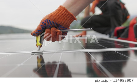 Technicians installing solar panels on metal stand. Workers installing solar panels on the roof of a house. Close-up Installation, Connection and mounting of solar panels. Workers fasten solar panels. 134988907