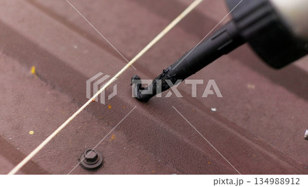 Close up of applying sealant on the roof. Carpenter repairing cabin roof of boat sealing leaks with mastic waterproof sealant 134988912