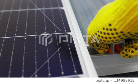 Mounting solar panel, installing solar panels on the roof of the house. Connection of solar panels. Close up of worker installing and working on maintenance of photovoltaic panel system installed Mounting solar panel, installing solar panels on the roof of the house. Connection of solar panels. Close up of worker installing and working on maintenance of photovoltaic panel system installed 134988919