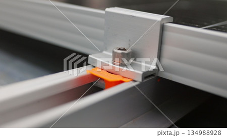 Close up of mounting solar panel, installing solar panels on the roof of the house. Fixing and connection of modern solar panels. Install photovoltaic panels on a metal basis on a solar farm. 134988928