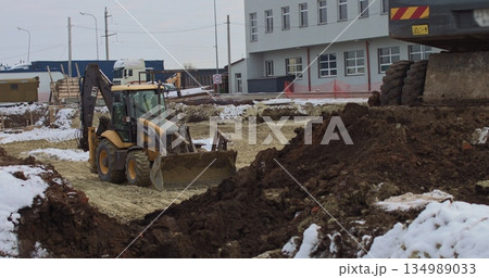 The bulldozer works on a construction site with sand, side view. New Big Tractor, a bulldozer on wheels on a sandy road on a construction site levels the site for the construction of real estate. 134989033