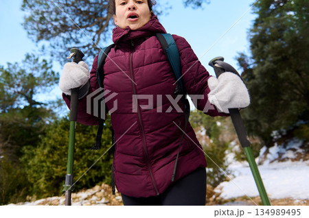 Woman Hiking in Winter Snow Outdoors With Trekking Poles and Warm Jacket Woman Hiking in Winter Snow Outdoors With Trekking Poles and Warm Jacket 134989495