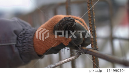 Engineers work with metal constructions while building a house. Twisting of a framework for pouring of concrete. Reinforcement of the foundation of the building with metal. Engineers work with metal constructions while building a house. Twisting of a framework for pouring of concrete. Reinforcement of the foundation of the building with metal. 134990304