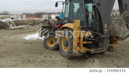 Construction Machinery At Work On Building A House. Different Types Of Tractors And Excavators Prepare The Soil For Plant Construction In The Industrial Zone. Bulldozer Rides on Sandy Road. Construction Machinery At Work On Building A House. Different Types Of Tractors And Excavators Prepare The Soil For Plant Construction In The Industrial Zone. Bulldozer Rides on Sandy Road. 134990331