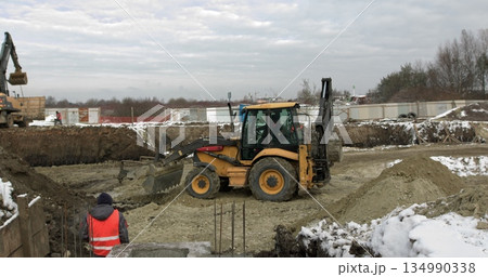 Loader excavator, bulldozer and roller work on construction site. Machines perform excavation work. Compaction of soil and rubble for residential buildings. Construction work. Loader excavator, bulldozer and roller work on construction site. Machines perform excavation work. Compaction of soil and rubble for residential buildings. Construction work. 134990338