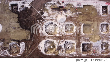 Aerial flight over a new construction site with heavy machinery and people building real estate. Filling the foundation of the building. Top to bottom view of contractors in protective caps. 134990372