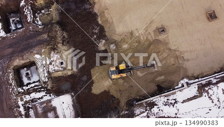 An Industrial Excavator On An Open Road Section Loads Rock And Earth On A Very Large Dump Truck, Loaded With Ore .The Excavator Bucket Drips And Loads The Ore.Panorama Of Construction Works 134990383