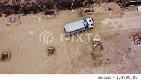 Truck laden with dirt and soil travels in a road construction complex site. Dump truck unloading soil or sand at construction site Truck laden with dirt and soil travels in a road construction complex site. Dump truck unloading soil or sand at construction site 134990388