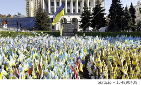 Many small blue-yellow flags with names of the dead war against russia. Memorial of the fallen soldiers, children, women in the capital of Ukraine. Concept of tragedy and misfortune. Close up Many small blue-yellow flags with names of the dead war against russia. Memorial of the fallen soldiers, children, women in the capital of Ukraine. Concept of tragedy and misfortune. Close up 134990439
